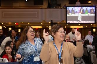 Two women at the 2024 UFT Paraprofessional Festival and Awards Luncheon react to the keynote address. 