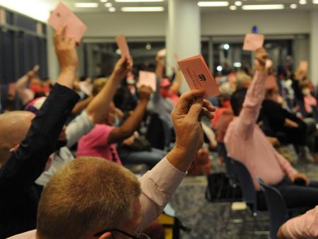 People raising hands with ballots