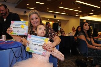 A teacher and her student hold up certificates at the 2024 Better Speech and Hearing Month Celebration at UFT Headquarters on May 30, 2024.