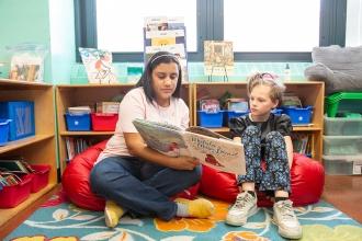 A teacher reads a book to her student