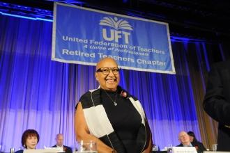 A woman smiles on stage while being honored at the 2024 UFT Retired Teachers Chapter Luncheon