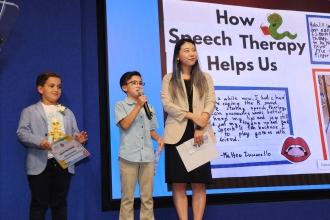 Speech provider Heather Park of PS 98 in Queens listens to her students describe their project at the 2024 UFT Better Speech and Hearing Month Celebration.