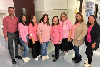 A group of staff at a public school in Queens wear matching pink attire for breast cancer awareness.