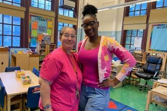 Two staff members at a school in the Bronx wear matching pink attire for breast cancer awareness. 