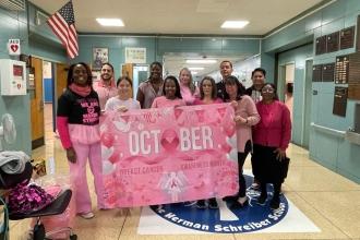 A group of staff at a public school in Brooklyn wear matching pink attire for breast cancer awareness.