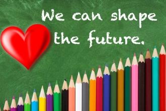 A graphic of a chalboard with a heart and writing that reads "We can shape the future." Colored pencils stack below. 