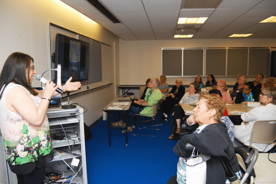 Speaker at a mike in a room full of classroom attendees