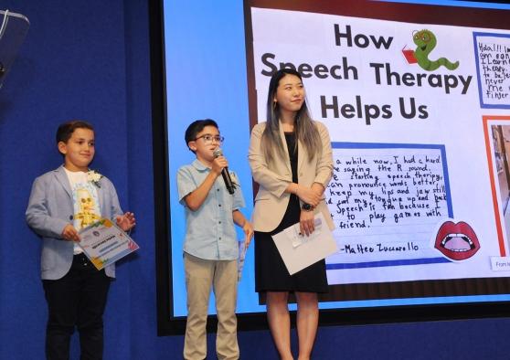 A speech teacher with her students on the stage at the UFT's Better Speech and Hearing Month Celebration